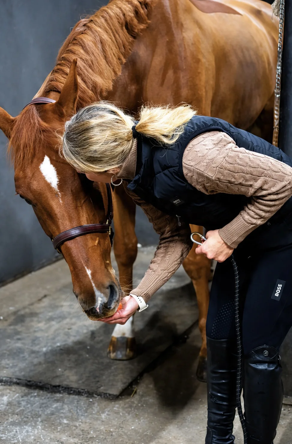 Linda leaning in to care for her horse in the stable